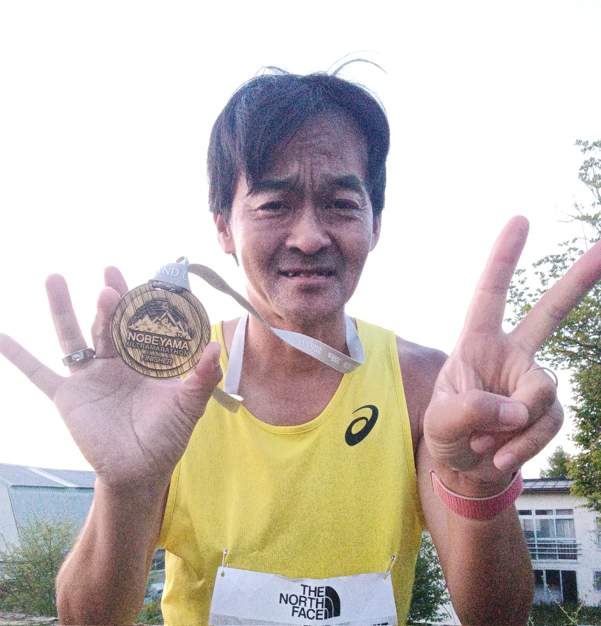 第32回野辺山ウルトラマラソンの完走メダルを掲げ、ピースサインをするバナナぴろしの完走記念写真