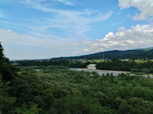 常願寺川沿いの広大な緑と山並み、夏空の下で光る川の流れ