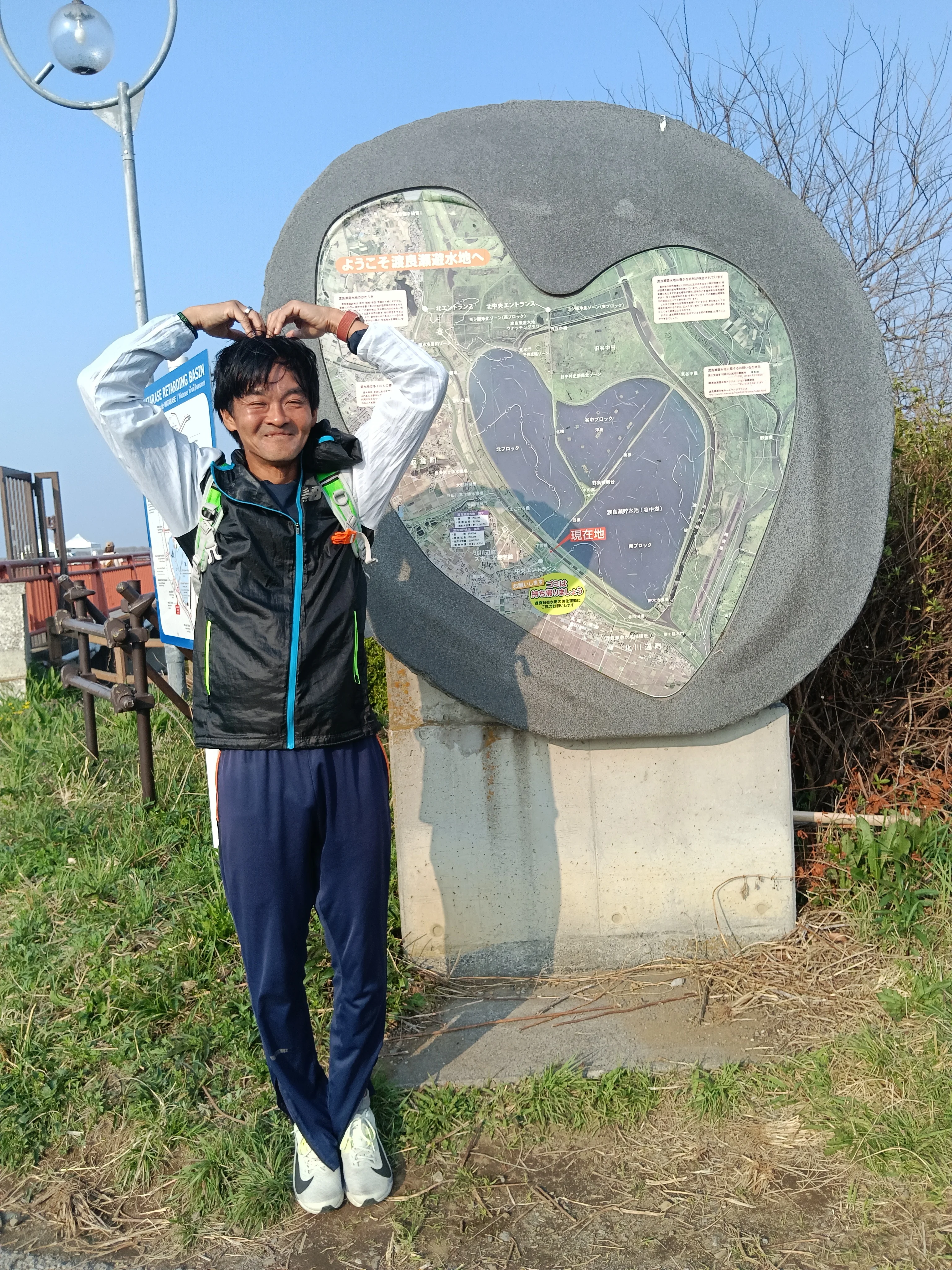 谷中湖のハート型モニュメント前でポーズするランナー - 60km走ゴール後の達成感