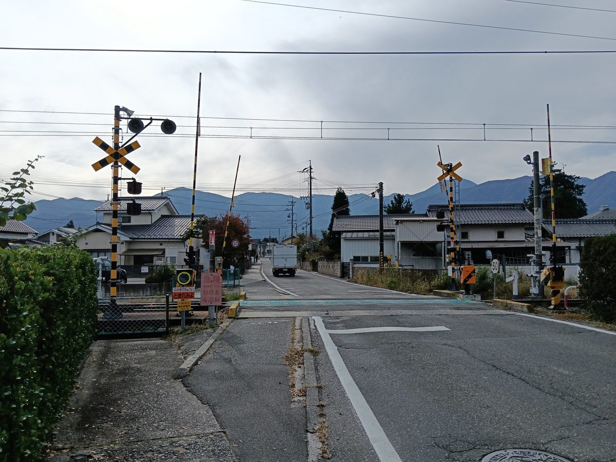 踏切のある道の向こうに、山並みが見える