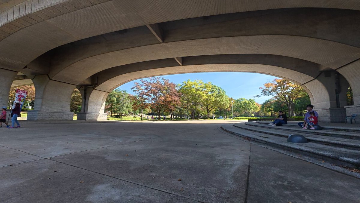 大きなアーチの道路の下をくぐる道。奥に芝生と木々